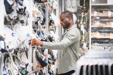 Büyük bir alışveriş merkezinde ayakkabı seçen şık bir adam perakende terapi deneyiminin tadını çıkarıyor.
