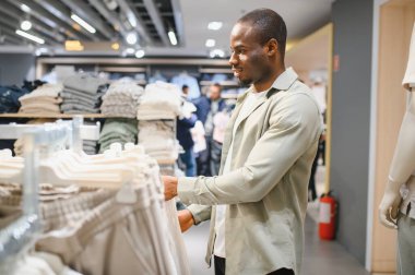 Bir perakende mağazasında moda kıyafetlere göz atmak, alışveriş deneyiminin tadını çıkarmak ve şık kıyafetler aramak.