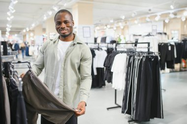 Bir giyim mağazasında alışveriş yaparken şık bir pantolon giyen müşteri, modern giyim ve moda trendlerinin seçiminin tadını çıkarıyor.