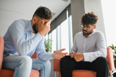 Erkek hasta terapi seansı sırasında psikologla sorunlarını tartışıyor.