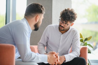 Psikolog terapi seansında erkek hastaların sorunlarını dinlerken not alıyor.