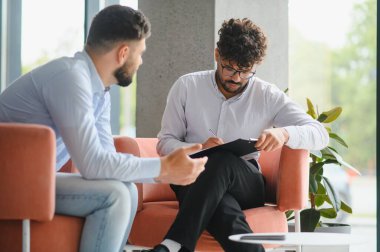 Psikolog, terapi seansı sırasında erkek hastaların sorunlarını anlatırken not alıyor.