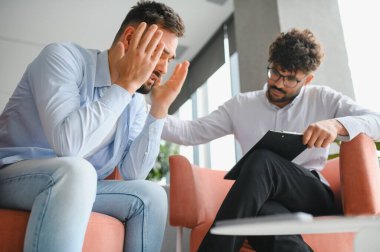 Anksiyete ve depresyon geçiren erkek hasta profesyonel psikologla psikoterapi seansı yapıyor.