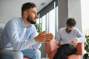 Hasta sorunlarını modern ofiste terapi seansında not alan psikologlara anlatıyor.