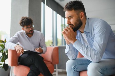 Psikolog, ofiste terapi seansı sırasında erkek hastaların sorunlarını dinlerken not alıyor.