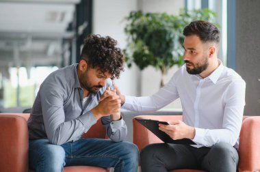 Terapi seansında genç bir adamı destekleyen psikolog, rahatlık ve anlayış sunuyor.