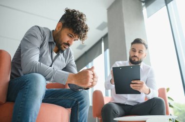 Modern ofiste terapi seansında not alan üzgün bir hasta psikologla sorunlar hakkında konuşuyor.