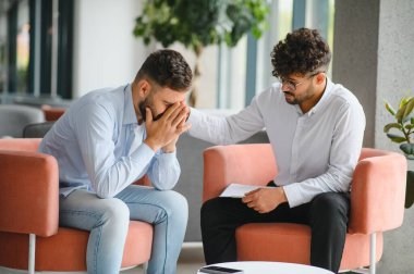 Depresyondan muzdarip bir erkek hasta psikologla terapi seansı yapıyor, sorunları hakkında konuşuyor.