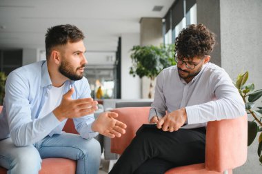 Hasta sorunlarını modern ofiste terapi seansında not alan psikologlara anlatıyor.