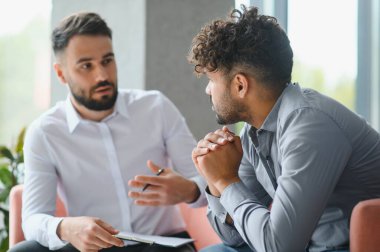 Terapi seansında üzgün bir Arap 'a ruh sağlığı desteği sağlayan psikolog sorunlarını tartışıyor ve rehberlik öneriyor.