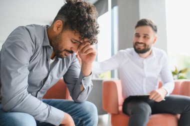 Terapi seansında iyileşme ve iyileşme odaklı travma geçiren üzgün bir Arap 'a destek veren psikolog.