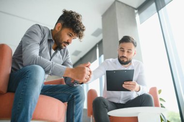 Psikolog, modern ofisteki terapi seansında hastayı üzecek notlar gösteriyor.