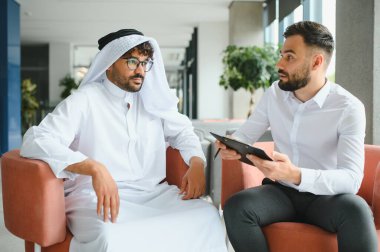 İki iş ortağı, geleneksel kandura 'da bir Arap adam ve batılı bir yönetici, bir toplantı yapıyorlar, planlar ve stratejileri tartışıyorlar.