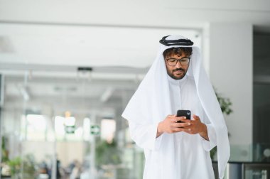 Parlak ofis alanında cep telefonu kullanan başarılı girişimci, gelenek ve teknoloji arasındaki bağlantıyı gösteriyor