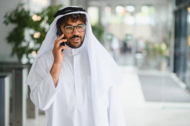 Başarılı bir girişimci, parlak, modern bir ofiste kültürel karışımı ve iş iletişimini gösteren bir telefon görüşmesi yapıyor.