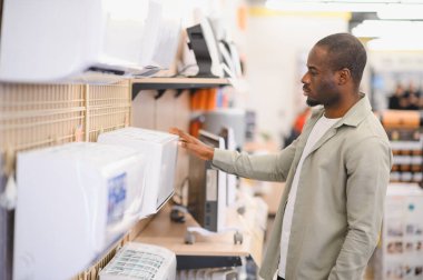 Alet dükkanından portatif klima seçen adam, ev soğutma çözümleri için alışveriş yapıyor.