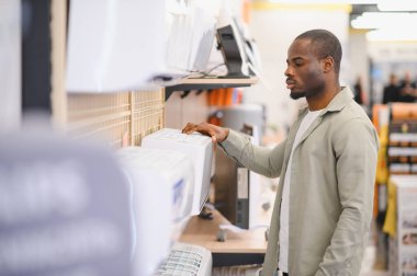 Alet dükkanından portatif klima seçen adam, ev soğutma çözümleri için alışveriş yapıyor.