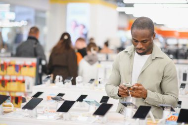 Müşteri akıllı telefonunu bir elektronik mağazasında cep telefonu özelliklerini ve fiyatlarını karşılaştırmak için kullanıyor