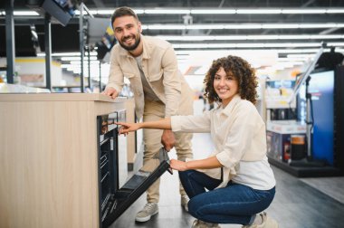 Ev aletleri mağazasında modern fırını seçen mutlu çift, mutfakları için satın alma kararı alıyorlar.