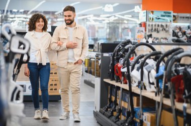 Bir çift elektronik mağazasına girip ev aletlerini karıştırıyor. İhtiyaçları için en iyi seçeneği seçmekle meşgul görünüyorlar.