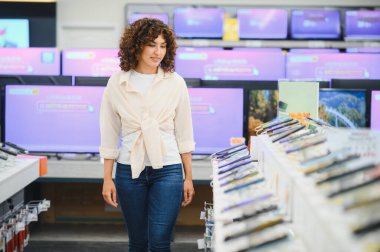 Tüketici elektroniği mağazasında yürüyen müşteri yeni akıllı telefon arıyor, farklı modeller seçiyor ve karşılaştırıyor