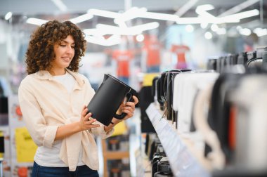 Müşteri elektrikli su ısıtıcısını ev aletleri mağazasında karşılaştırıyor, mutfak eşyaları için satın alma kararları alıyor.