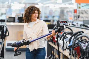 Müşteri elektronik mağazasından kablosuz elektrik süpürgesi seçiyor, seçenekleri değerlendiriyor ve bilgilendirilmiş bir satın alma için özellikleri karşılaştırıyor