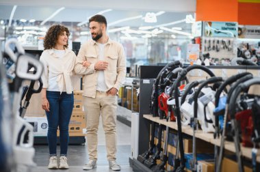 Mutlu çift elektronik mağazasında birlikte alışveriş yapıyor, yeni bir elektrikli süpürge seçiyor seçenekleri tartışıyor ve eğleniyorlar.