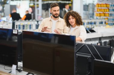 Müşteriler, bir tüketici elektronik mağazasında televizyonlarını karşılaştırıyor, ev eğlenceleri için satın alma kararları alıyorlar.