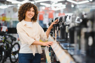 Müşteri, perakende satış mağazasından ev aletleri alırken çeşitli kahve makinelerini karşılaştırıyor.