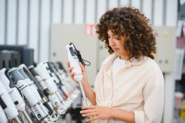 Müşteri ev aletleri mağazasında el bilgisayarı karıştırıcısını inceliyor, mutfak için satın alma kararı veriyor