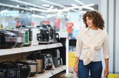 Müşteri, modern mutfak kolaylığı için çeşitli seçenekleri göz önünde bulundurarak, bir ev aletleri mağazasında çoklu fırın seçimi inceliyor