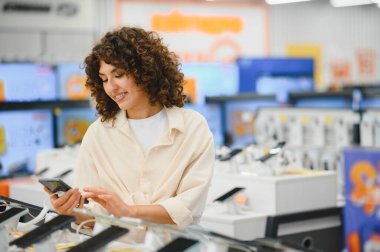 Müşteri, elektronik mağazasında akıllı telefonunu kullanarak cep telefonlarını karşılaştırıyor ve bilgilendirilmiş satın alma kararları veriyor.