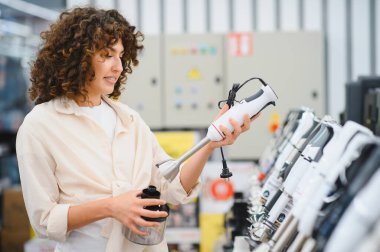 Müşteri ev aletleri mağazasında el bilgisayarı karıştırıcısını inceliyor, mutfak ekipmanları için satın alma kararı veriyor