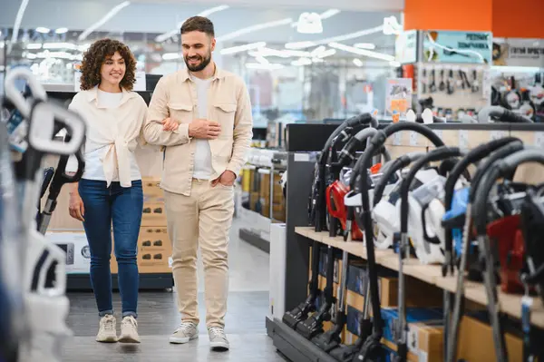 Bir çift elektronik mağazasına girip ev aletlerini karıştırıyor. İhtiyaçları için en iyi seçeneği seçmekle meşgul görünüyorlar.