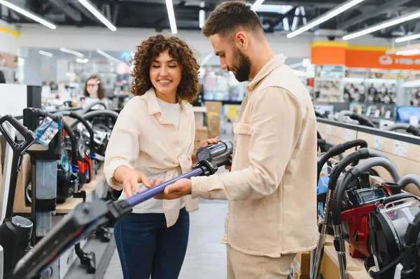 Mutlu çift yeni bir elektrikli süpürge seçiyor, elektronik mağazasında birlikte alışveriş yapıyorlar, evleri için satın alma kararı veriyorlar.
