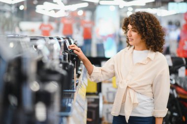 Müşteri bir mağazadan kahve makinesi seçiyor, satın almadan önce çeşitli modelleri keşfediyor.