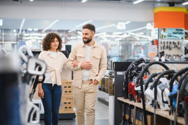 Elektronik mağazasında gezen mutlu çift yeni evleri için mükemmel bir elektrikli süpürge seçiyorlar.