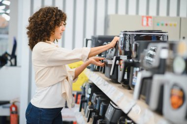 Müşteri bir ev aletleri mağazasından yeni bir kahve makinesi seçiyor, satın almadan önce özellikleri ve fiyatları karşılaştırıyor