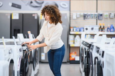 Müşteri ev aletleri mağazasından yeni çamaşır makinesi seçiyor, özellikleri inceliyor ve satın alma kararı veriyor
