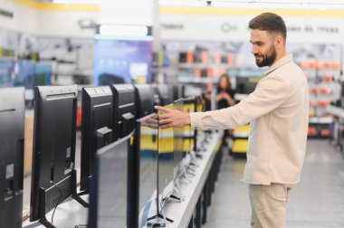 Müşteri, tüketici elektroniği mağazasındaki yeni televizyonları karşılaştırıyor, satın almadan önce karar veriyor