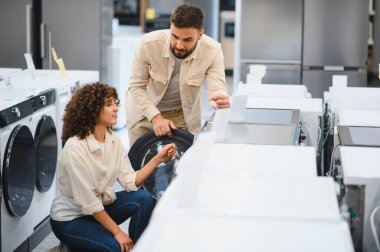 Çamaşır makinelerini karşılaştıran çiftler, okuma özellikleri ve enerji etiketleri, ev aletleri mağazasında satın alma kararı