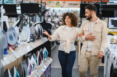 Genç çift bir ev aletleri dükkanına girip çeşitli ev eşyaları ve eşyalar arasından mükemmel demiri seçiyor.