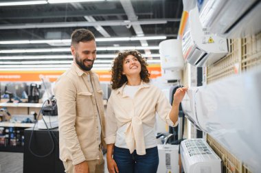Gülümseyen bir çift yeni bir klima seçiyor ve evleri için en iyi seçeneği arıyor.