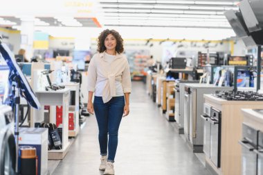 Müşteri bir elektronik mağazasına giriyor, çeşitli ev aletlerine bakıyor ve modern mutfak güncellemeleri için seçenekler düşünüyor.