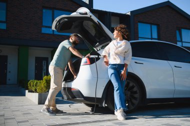 Evde elektrikli araçlarını şarj eden çift, ekolojik bilinçli yaşama ve sürdürülebilir taşımaya doğru kaymayı vurguluyor