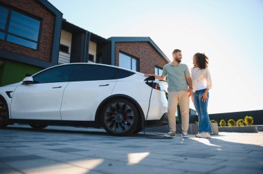 Mutlu ev sahipleri elektrikli araçlarını şarj ediyor, sürdürülebilir yaşamın tadını çıkarıyor ve karbon ayak izlerini azaltıyor.