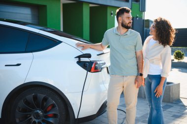 Mutlu ev sahipleri elektrikli araçlarını şarj ediyor, sürdürülebilir yaşamın tadını çıkarıyor ve karbon ayak izlerini azaltıyor.