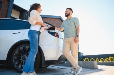 Ev sahipleri elektrikli araçlarını şarj ederek sürdürülebilir uygulamaları tartışıyor ve yeşil enerjinin faydalarından faydalanıyorlar.