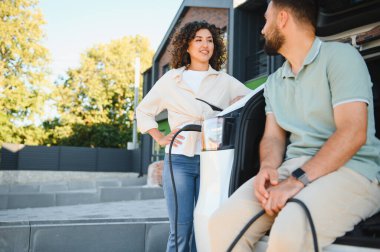 Çift elektrikli araçlarını evde şarj ediyor, çevre dostu ulaşım ve yenilenebilir enerji çözümlerine bağlılıklarını gösteriyor